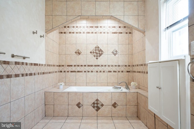 bathroom with tile walls, tile patterned floors, plenty of natural light, and a relaxing tiled tub