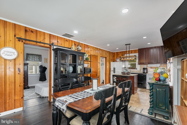 dining space with wooden walls, hardwood / wood-style floors, and a barn door