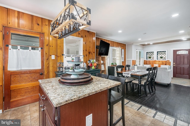 kitchen featuring light stone countertops, wood walls, light hardwood / wood-style floors, and a center island