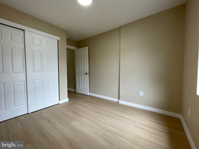 unfurnished bedroom with light wood-type flooring and a closet