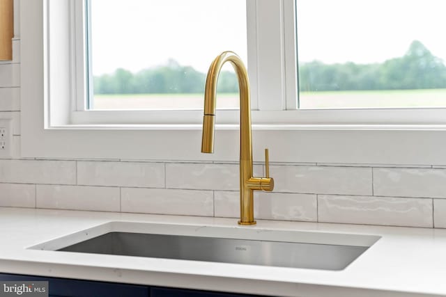 room details with tasteful backsplash, sink, and light stone counters