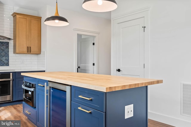 kitchen featuring oven, wood counters, hanging light fixtures, beverage cooler, and dark wood-type flooring