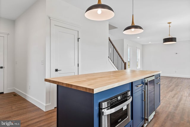 kitchen with dark hardwood / wood-style flooring, wood counters, blue cabinetry, decorative light fixtures, and a center island