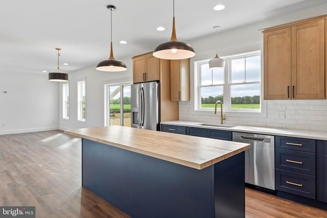 kitchen with a center island, a healthy amount of sunlight, stainless steel appliances, and butcher block counters