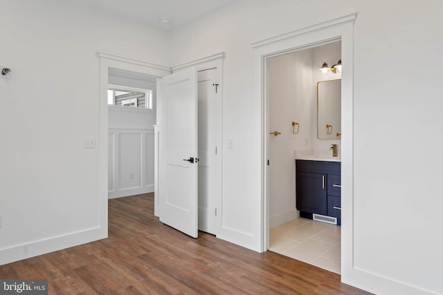 unfurnished bedroom with ensuite bathroom, sink, and dark hardwood / wood-style floors