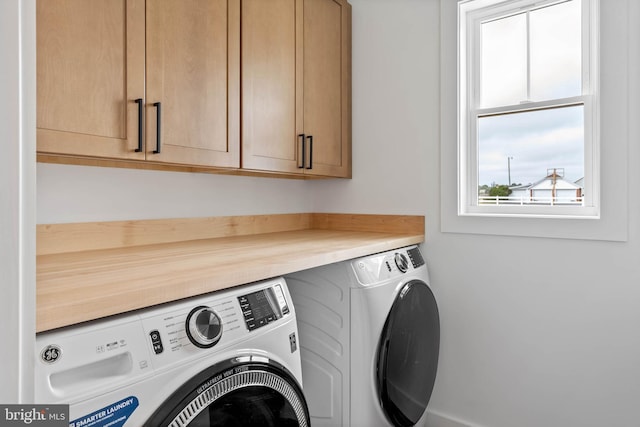 clothes washing area featuring washing machine and dryer and cabinets