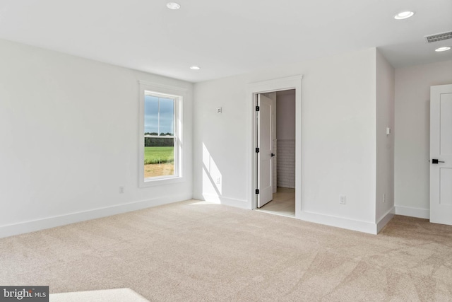 interior space with connected bathroom and light colored carpet