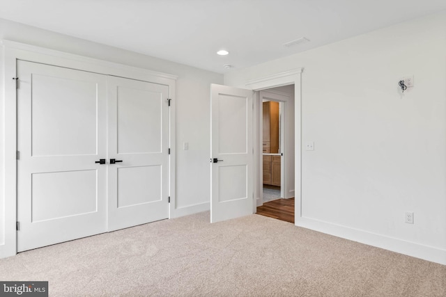 unfurnished bedroom featuring a closet and light carpet