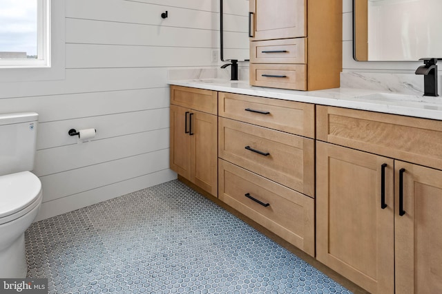 bathroom featuring vanity, toilet, and wooden walls