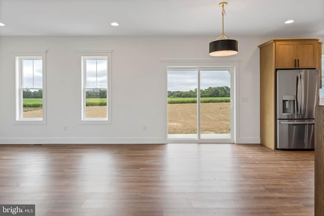 interior space with wood-type flooring, plenty of natural light, and stainless steel refrigerator with ice dispenser