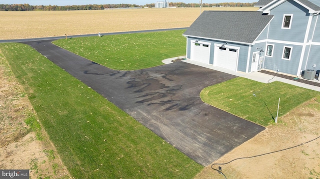 exterior space featuring central air condition unit, a garage, and a rural view