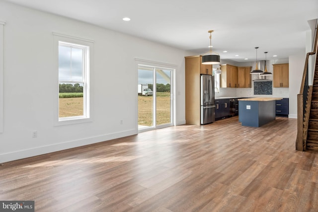 kitchen with plenty of natural light, stainless steel fridge, pendant lighting, and a kitchen island