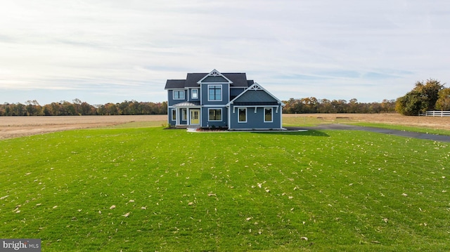 view of front of house with a rural view and a front lawn