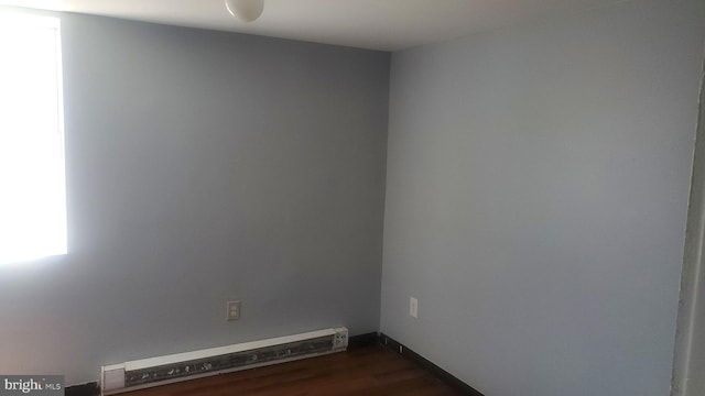 spare room with dark wood-type flooring and a baseboard radiator