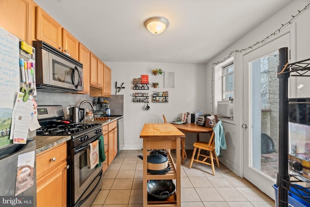 kitchen with dark stone counters, tasteful backsplash, stainless steel appliances, light brown cabinets, and light tile patterned floors