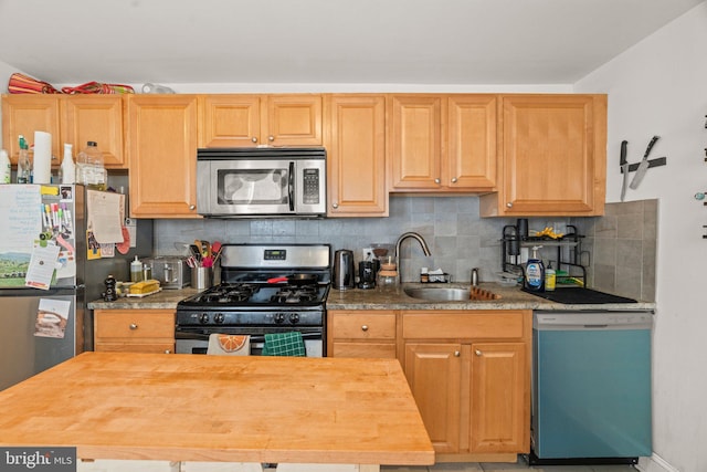 kitchen featuring appliances with stainless steel finishes, backsplash, wood counters, and sink