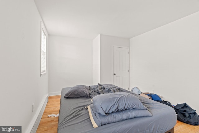 bedroom with a baseboard heating unit and hardwood / wood-style flooring