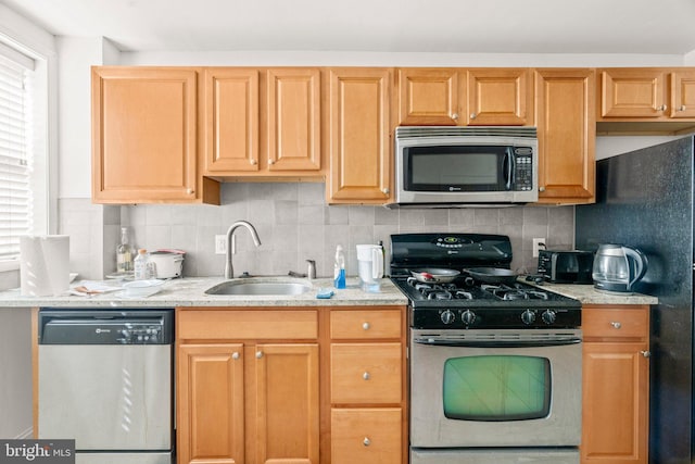 kitchen featuring light stone counters, appliances with stainless steel finishes, sink, and tasteful backsplash