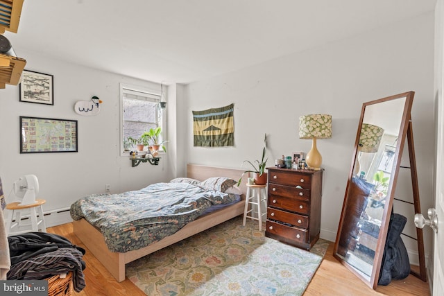 bedroom with a baseboard radiator and light hardwood / wood-style flooring