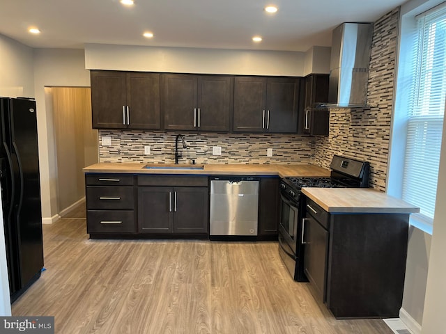 kitchen featuring tasteful backsplash, sink, wall chimney exhaust hood, stainless steel appliances, and light hardwood / wood-style flooring