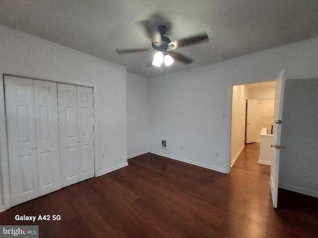 unfurnished bedroom with ceiling fan, a closet, and dark wood-type flooring