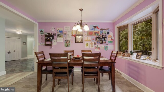 dining space featuring wood-type flooring, ornamental molding, and an inviting chandelier