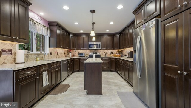 kitchen with dark brown cabinetry, appliances with stainless steel finishes, hanging light fixtures, and a center island