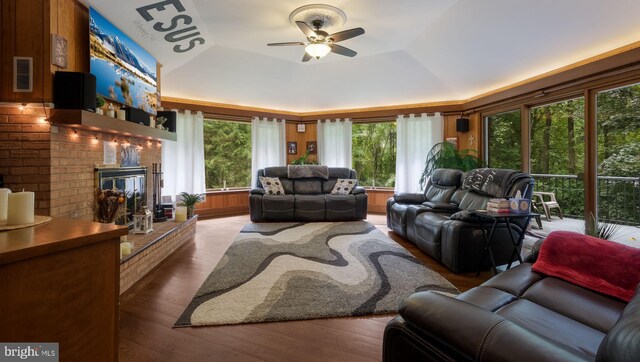 living room with hardwood / wood-style flooring, a raised ceiling, ceiling fan, and a brick fireplace