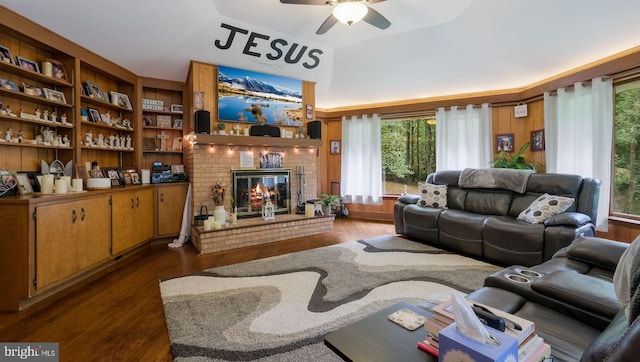 living room with a healthy amount of sunlight, a fireplace, ceiling fan, and dark wood-type flooring