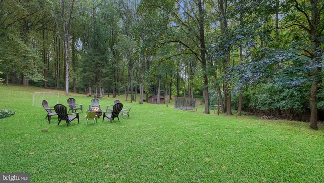 view of home's community featuring a lawn, a trampoline, and a fire pit