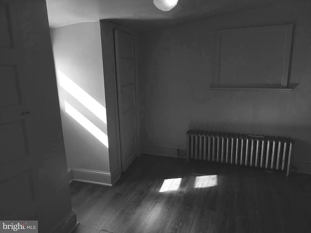 spare room featuring radiator and dark hardwood / wood-style flooring