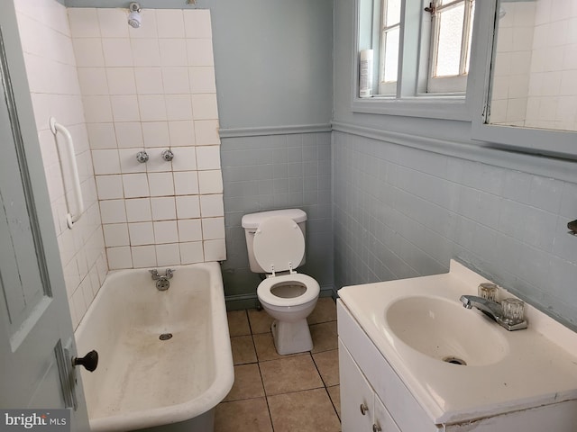 bathroom with vanity, toilet, a bathing tub, tile walls, and tile patterned flooring