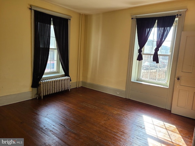 spare room with radiator, a wealth of natural light, and dark hardwood / wood-style floors