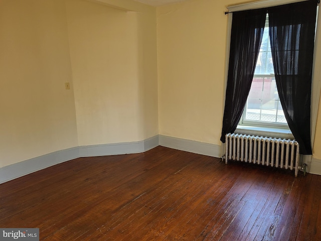 spare room with dark hardwood / wood-style flooring and radiator heating unit