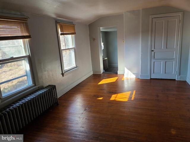 unfurnished room featuring lofted ceiling, dark hardwood / wood-style floors, and radiator heating unit