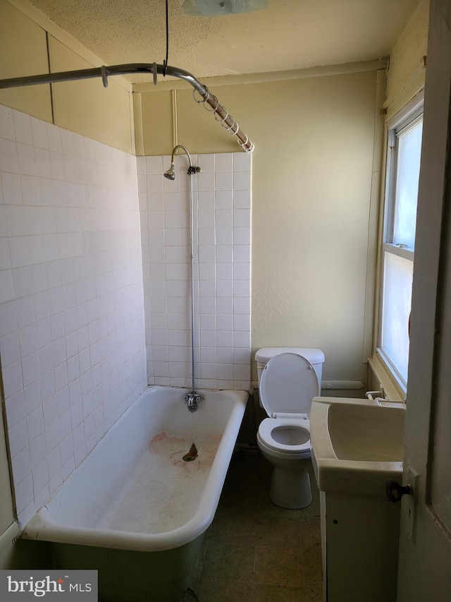 full bathroom with a textured ceiling, tile patterned floors, vanity, tiled shower / bath, and toilet