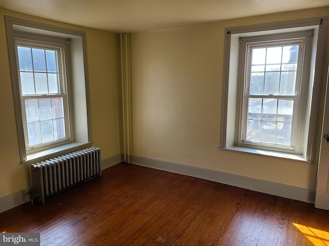 spare room with dark hardwood / wood-style floors and radiator heating unit