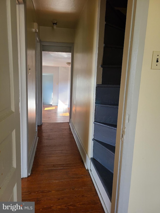 hall with a textured ceiling and dark wood-type flooring