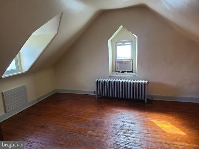 bonus room with cooling unit, radiator, lofted ceiling, and dark wood-type flooring