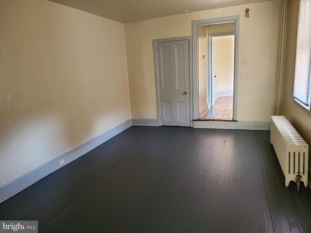 spare room featuring dark hardwood / wood-style flooring and radiator heating unit