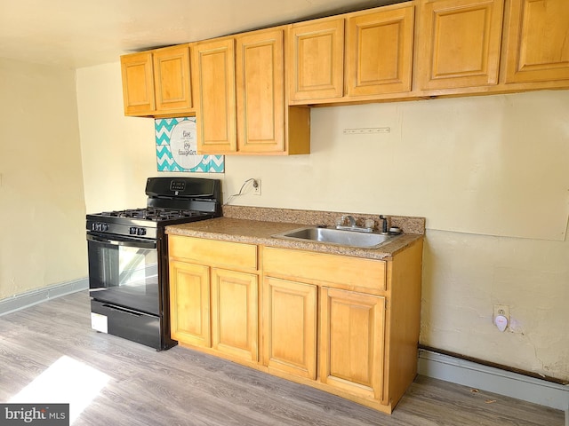 kitchen featuring black gas range, light wood-type flooring, and sink