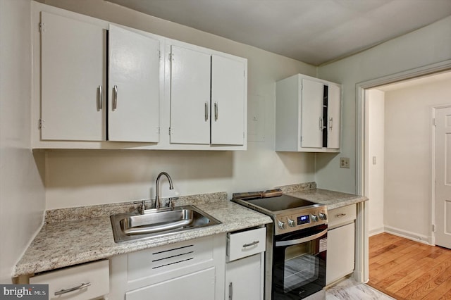 kitchen with light hardwood / wood-style floors, white cabinetry, sink, and stainless steel range with electric cooktop