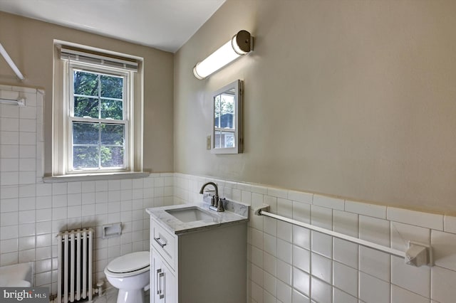 bathroom featuring tile walls, vanity, toilet, and radiator heating unit