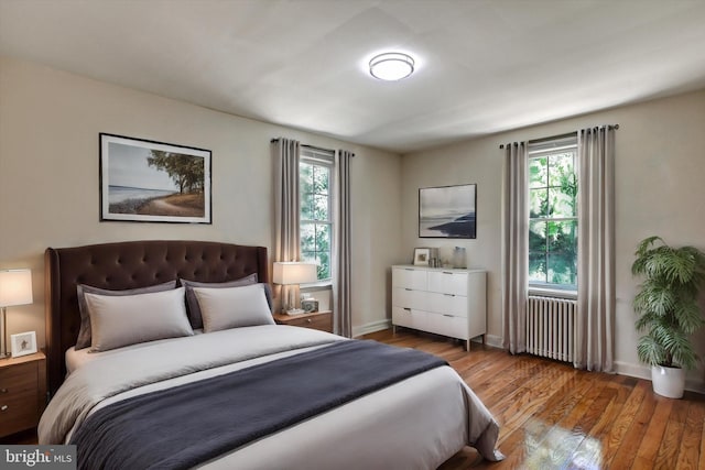 bedroom with radiator, multiple windows, and light wood-type flooring