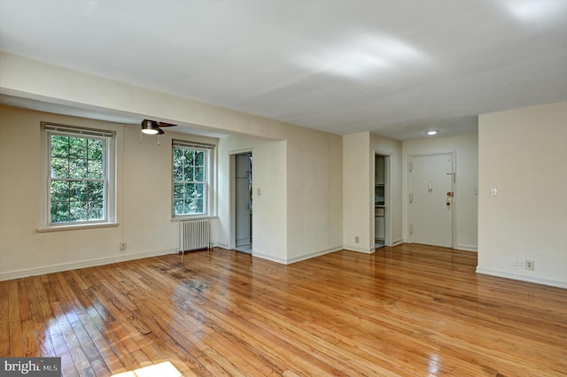 spare room with ceiling fan, light wood-type flooring, and radiator heating unit