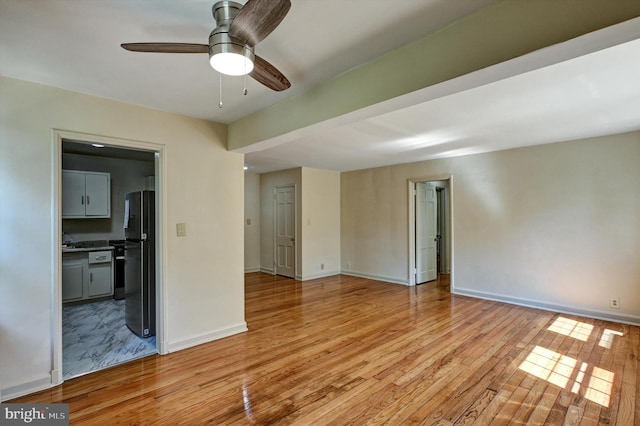 empty room with ceiling fan and light hardwood / wood-style flooring