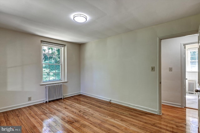 spare room with plenty of natural light, light hardwood / wood-style floors, and radiator heating unit