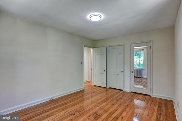 unfurnished bedroom with radiator heating unit and light hardwood / wood-style floors