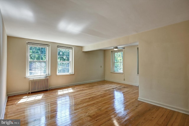 spare room with light wood-type flooring, a healthy amount of sunlight, and radiator heating unit