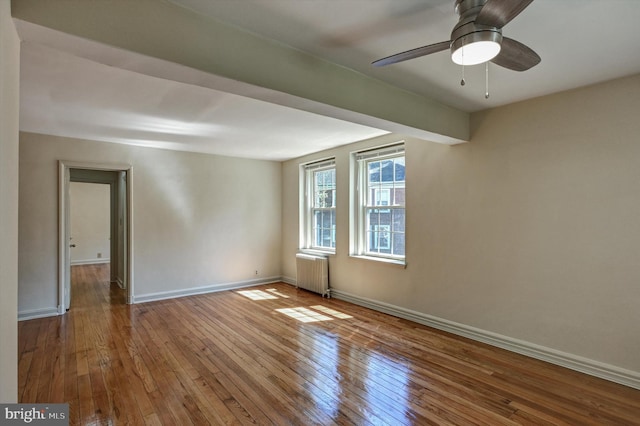 empty room featuring wood-type flooring, radiator, and ceiling fan